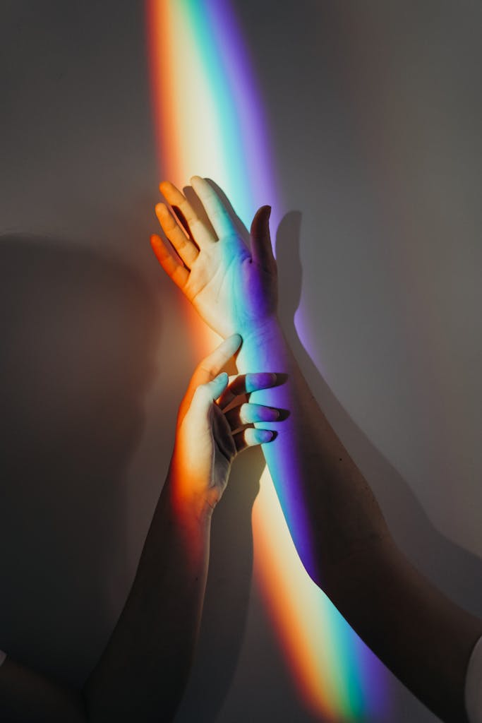 Relational Trauma. A beautiful display of rainbow light casting on intertwined hands symbolizing unity and love.
