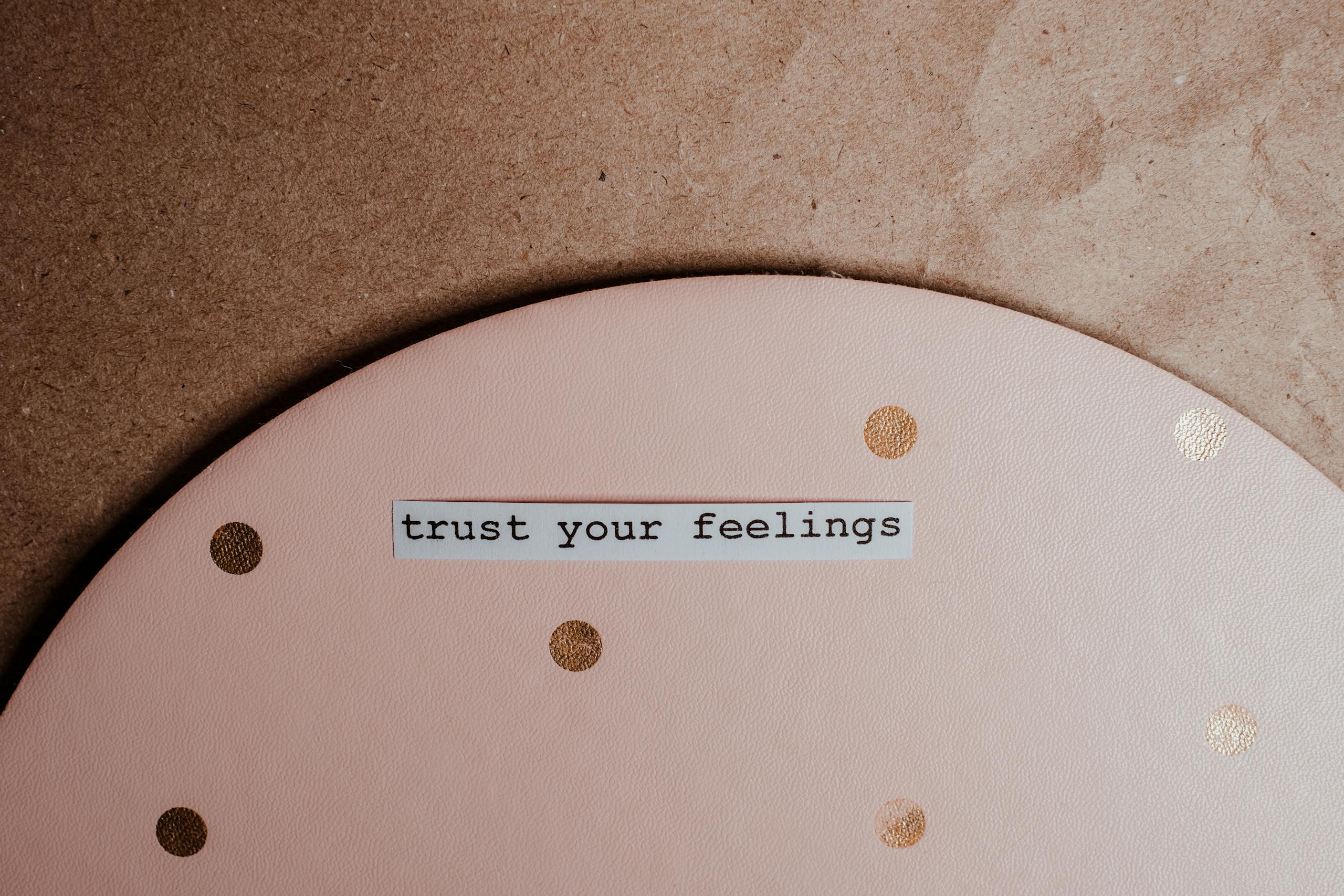 Close-up of a motivational message 'trust your feelings' on a pink polka dot and brown background.