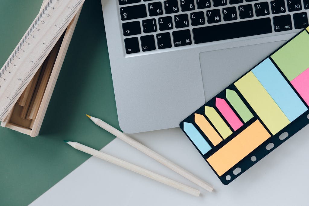 ADHD and Depression Organization Strategies: Organized desk with a laptop, sticky notes, pencils, and a ruler on green and white surface.