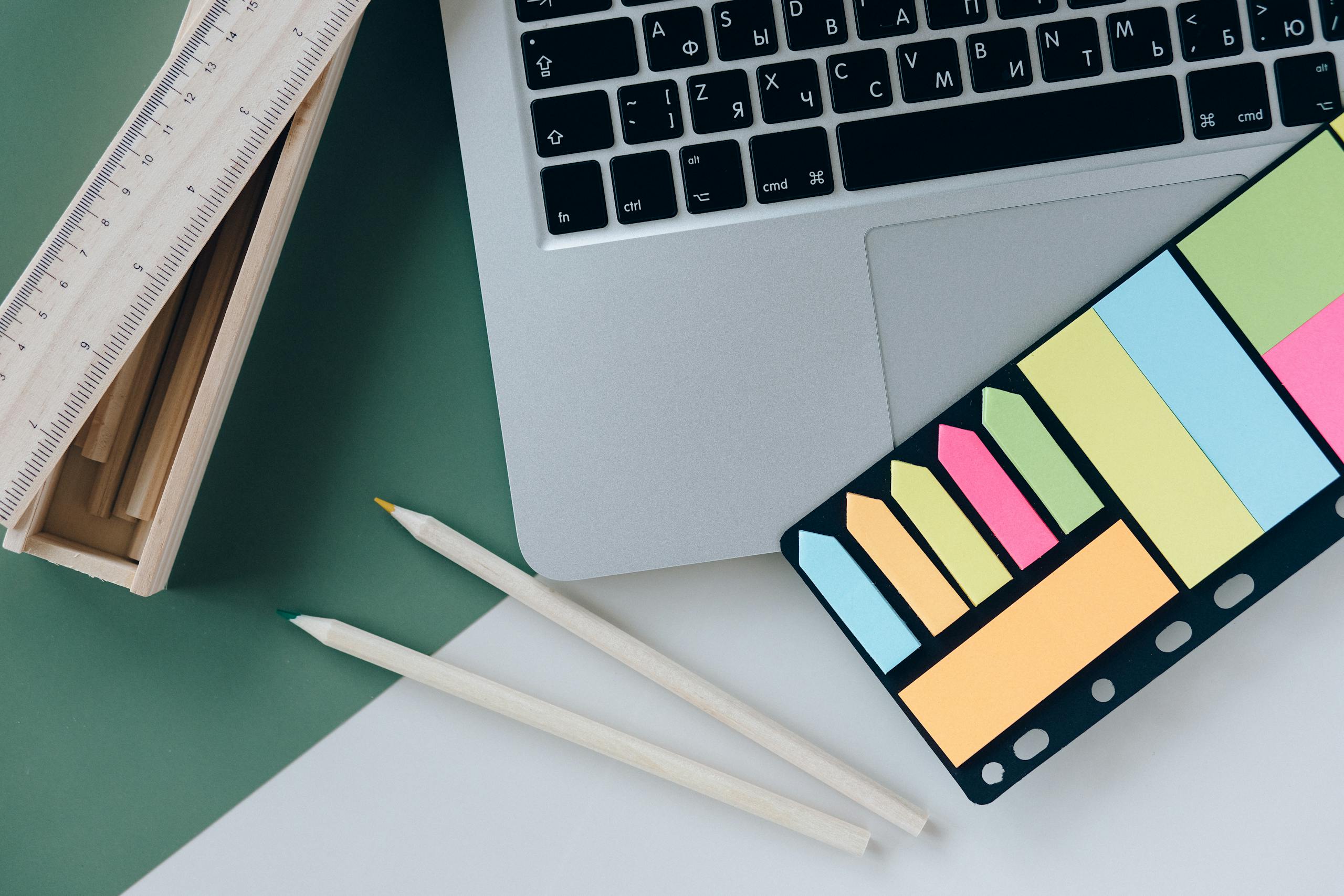 ADHD and Depression Organization Strategies: Organized desk with a laptop, sticky notes, pencils, and a ruler on green and white surface.